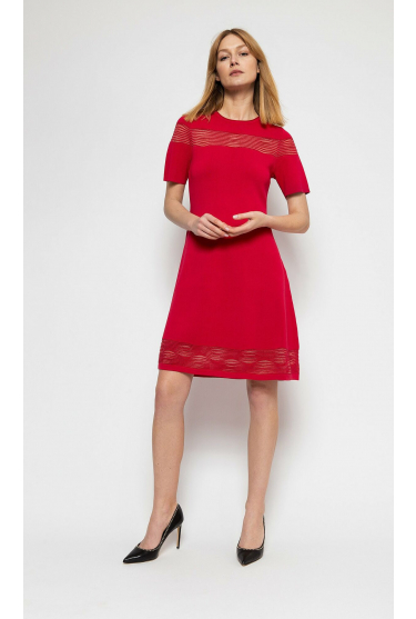 Czerwona, dzianinowa sukienka z krótkim rękawem, rozkloszowanym dołem oraz ozdobnymi przezroczystościami